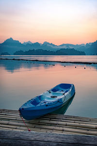 Boat moored in lake against sky during sunset