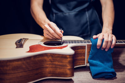 Midsection of man repairing guitar