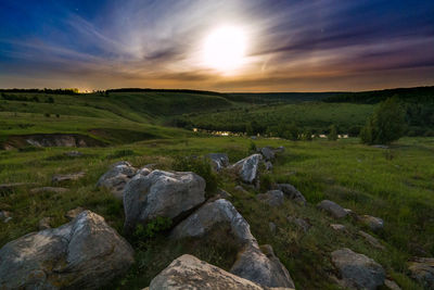 Natural moon halo summer starry night wide angle landscape with white rocks in a foreground