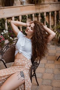 Portrait of young woman sitting on footpath