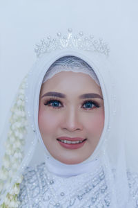 Portrait of young woman wearing hijab against white background