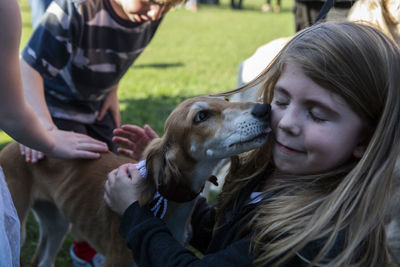 Close-up of dog licking girl on field