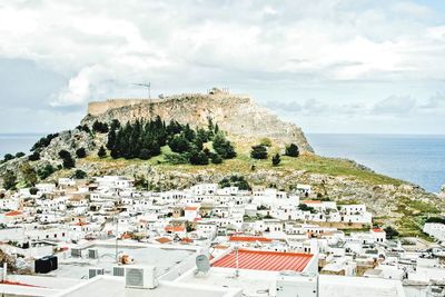 Town by sea against cloudy sky