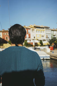 Rear view of man against buildings against clear sky