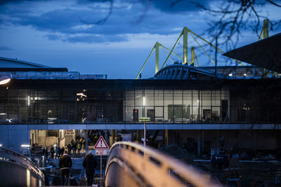 People at illuminated bridge in city against sky