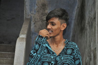 Close-up of smiling young man standing against wall