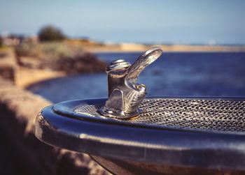 Close-up of faucet at beach against blue sky