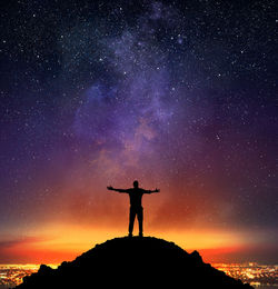 Silhouette man standing on rock against sky at night