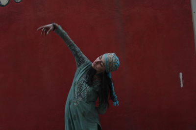 Young woman looking away against red wall