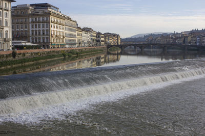 Bridge over river against buildings in city