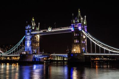 Illuminated suspension bridge over river at night