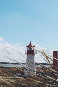 Low angle view of lighthouse by building against sky