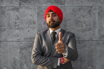 Portrait of smiling businessman wearing turban against wall