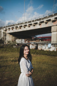 Portrait of smiling young woman standing against sky