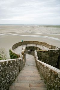 Footpath leading towards sea against sky