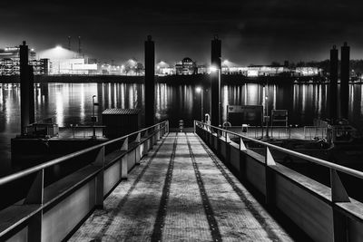 Illuminated bridge over river in city against sky at night