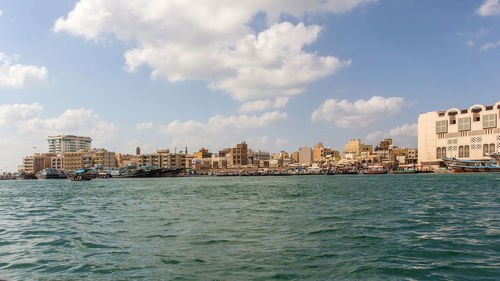 Sea by buildings against sky in city