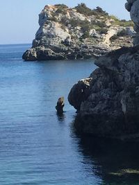 Rock formation in sea against sky