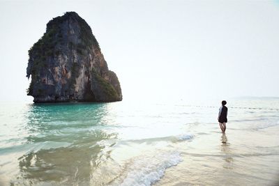 Man walking on beach against clear sky