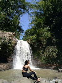 Side view of man against waterfall in forest