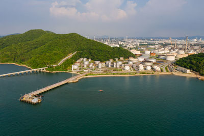 Aerial view of large fuel storage tanks at oil refinery industrial zone and the sea with bridge 