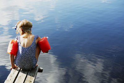 Girl sitting on jetty in water wings