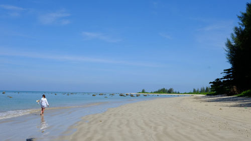 Rear view of woman on beach against sky