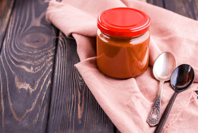 High angle view of hand holding glass jar on table