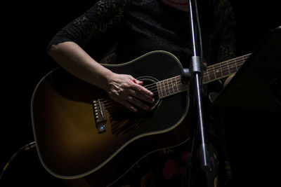 Midsection of man playing guitar at concert