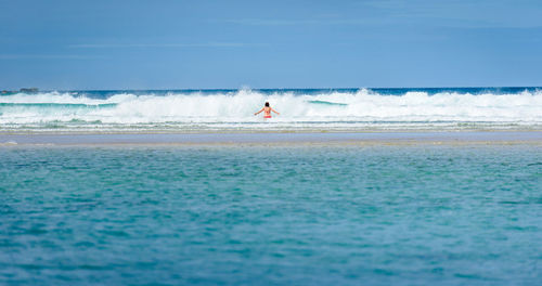 Rear view of woman in sea against blue sky