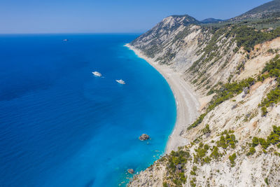 High angle view of sea and mountains against blue sky