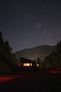 Illuminated car on field with mountain in background at night