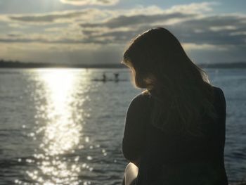 Rear view of woman looking at sea against sky during sunset