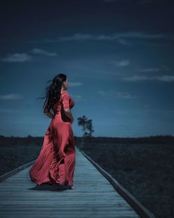 Side view of woman standing on road against sky