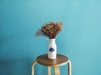 Close-up of vase on table against blue wall