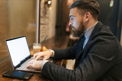 Freelancer using laptop typing at restaurant