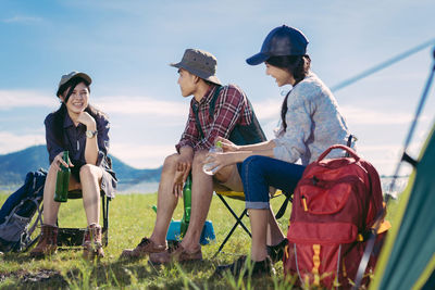 Friends sitting on chairs against sky