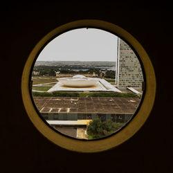 Buildings seen through glass window against clear sky