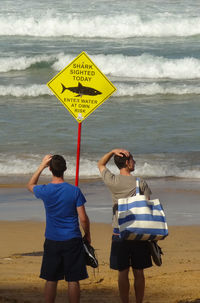 Rear view of people standing on beach