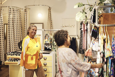 Smiling sales person with disability looking at female customer doing shopping at store