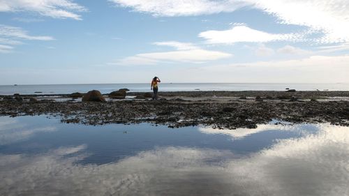 Mid distance view of woman standing on sand at beach