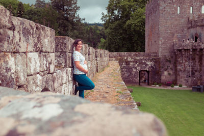 Woman standing on rock against wall