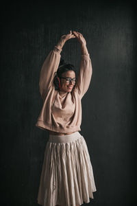 Portrait of young woman standing against black background