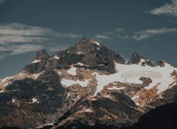 Rock formations on snow covered mountain against sky