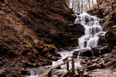 Cascading down a small mountain stream, the water runs over basalt boulders. a small waterfall runs 