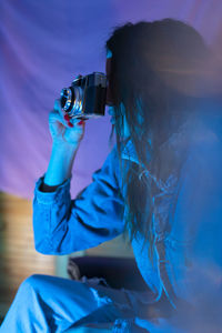 Rear view of woman photographing in blue drinking glass