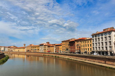 Buildings by river against sky in city