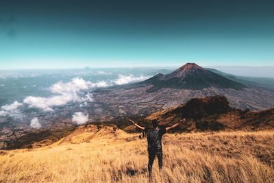 Rear view of man standing on mountain against sky