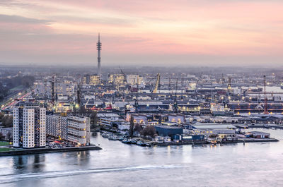 Aerial view of river and cityscape against cloudy sky during sunset