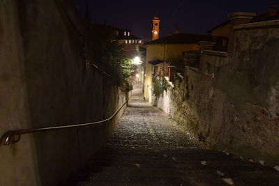 Walkway amidst illuminated buildings at night